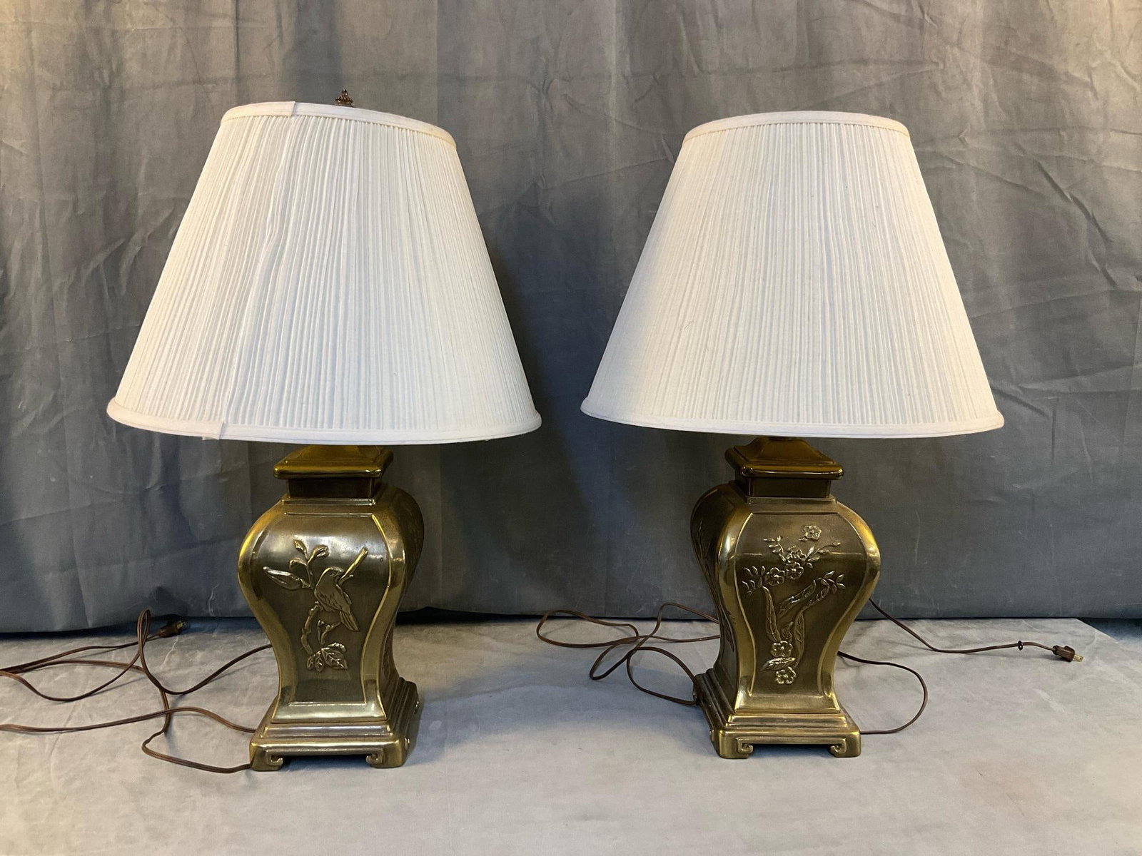 Chinese Lamps: Pair of contemporary brass Chinese style lamps with shades. Non matching finials. Lampshades in used condition with one shade having dents and cracks, otherwise good condition.Tested and works.