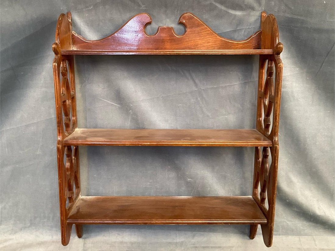 Wall Shelf: Late 20th century Chippendale style walnut open three-tier wall shelf. Missing finial, otherwise good condition. Measures 20.25 inches wide x 6.5 x 25 inches tall.