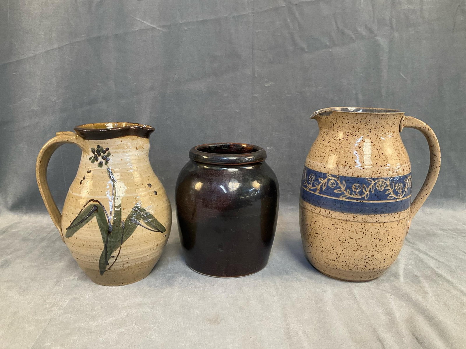 Art Pottery: Three pieces of late 20th century Art pottery. Unmarked crock with Albany slip glaze. Pitcher with illegible signature marked "‘82" with green floral decoration. Pitcher with incised floral decorati