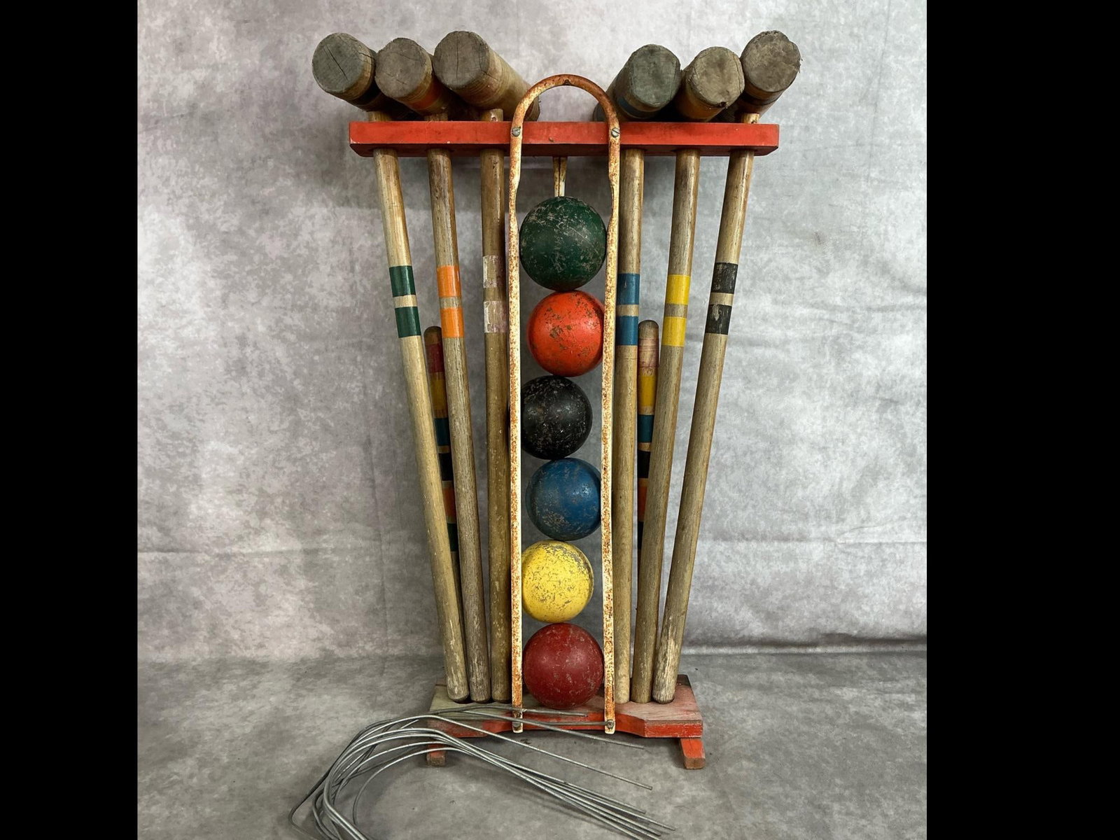 Vintage Croquet Set: Mid 1900's 6 person croquet set. Includes mallets with painted stripes, wooden balls, wickets, and wooden and metal rack. Rust present, stand is wobbly, and wear from age. Measures 15.5 inches wide x