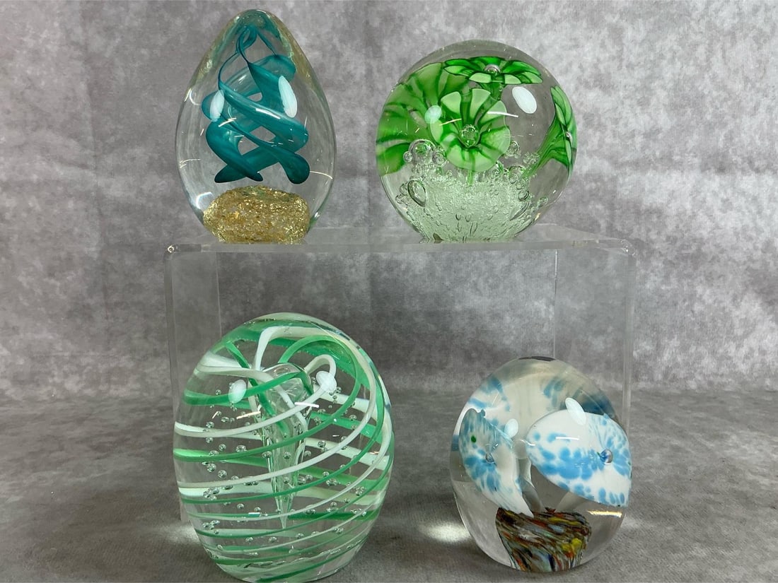 Unique Art Glass Paperweights: Four vintage paperweights. Large clear glass with green and white swirl around an inner cone is marked Gentile Glass, and blue and white flower shapes with multicolored base labeled Lutetian Glass. In