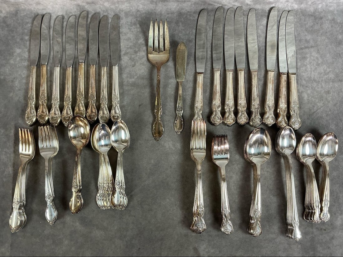 Silver-Plated Flatware: Two sets of WM Roger's silver-plated 8 place setting flatware. Includes 56 pieces of Baroque Rose pattern and 50 pieces of Victorian Rose. Some tarnish present. Knives measure 9 inches long x 1 inch w