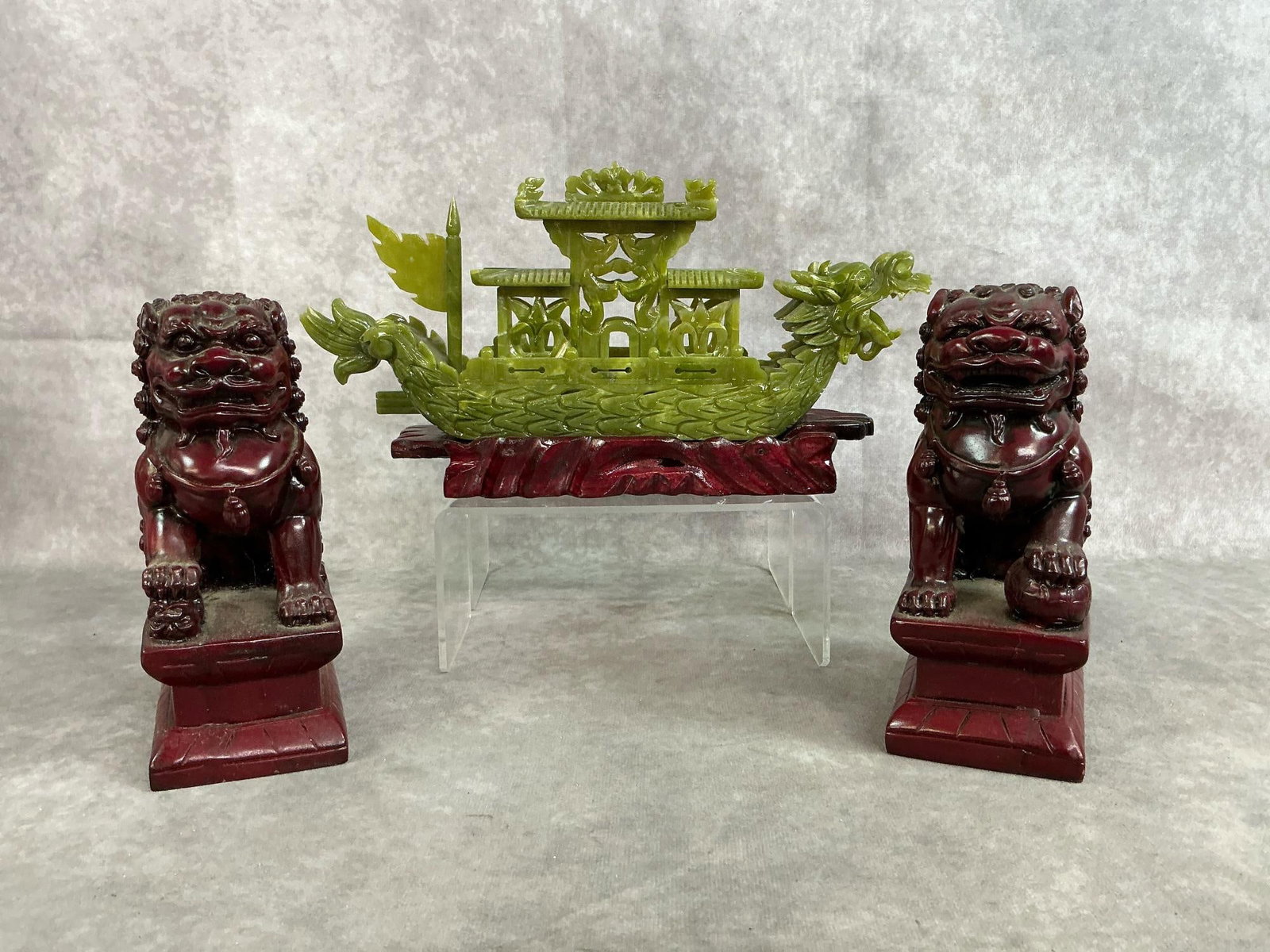 Asian Decor: Three modern Chinese style decorative items includes jade hand carved dragon ship with wooden stand and faux rosewood resin Foo Dogs. Ship is missing top sail and has chips to the top and tail, Foo