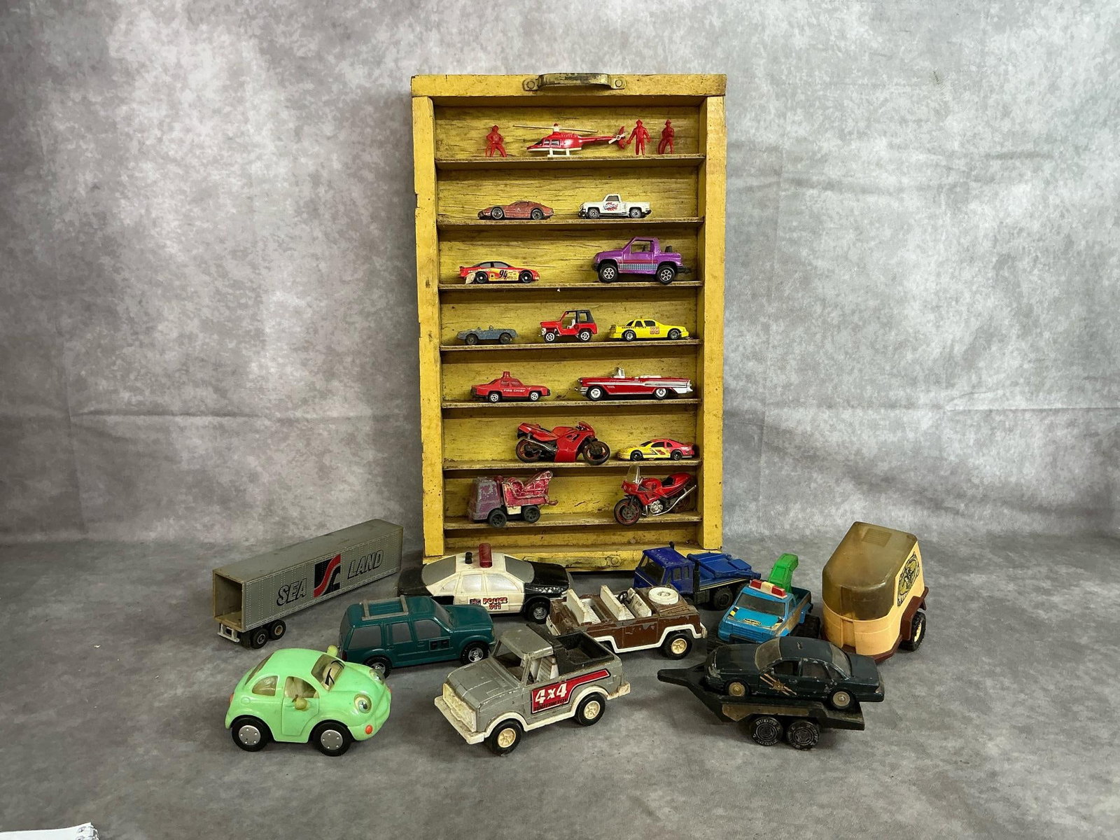 Toy Cars & Display Box: Twenty four mid to late 1900's cars and more. Wooden homemade display box with varied sizes and makes of toy cars. Includes Tootsie Toy, Chevron, Hot wheels and more. Rust, wear, and color fade presen