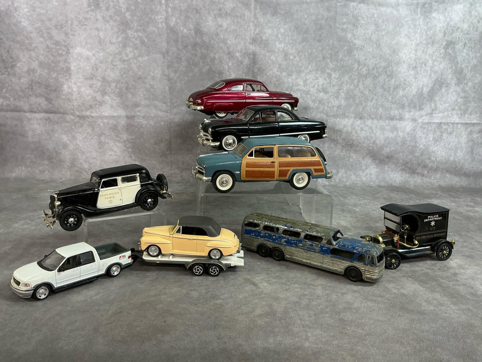 Collectible Cars: Eight late 1900's die cast cars. Includes Mercury, Cadillac, Woody Wagon,Tootsie Toy Greyhound bus, Model T Police wagon, and more. Rust present on bus, Police wagon is missing a wheel, otherwise vehi