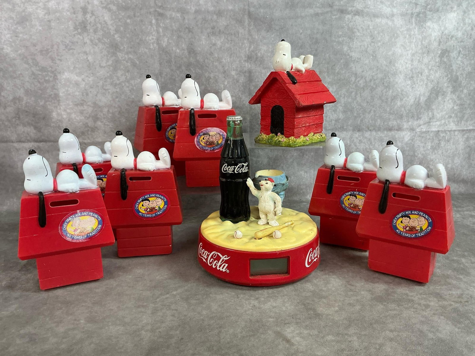 Snoopy Banks & Coke Clock: Ten late 1900's banks and clock. Seven plastic snoopy banks and a ceramic snoopy bank. Coca-cola baseball theme clock. Clock is untested and missing part of the larger bear. Clock measures 7 inches in