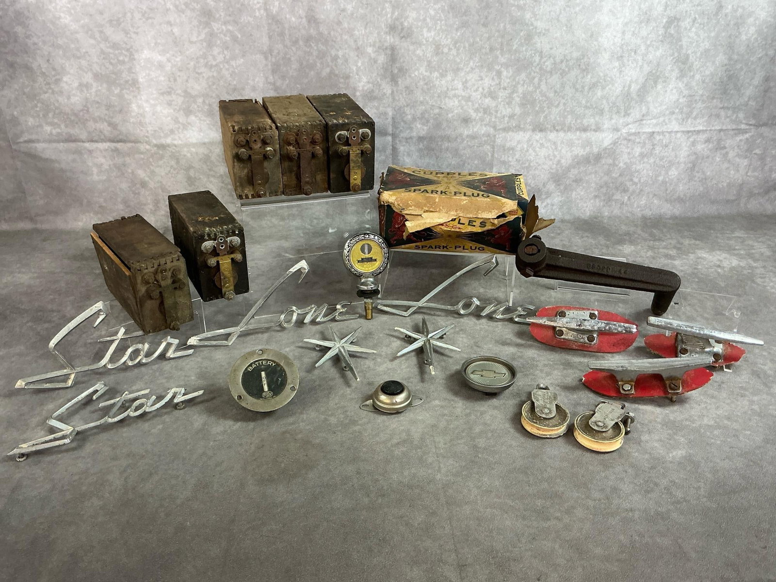 Ignition Coils, Gauges, Emblems & More: Twenty nine car and boat items. Five Ford Model T wooden cased ignition coil boxes. Box of Cupples Spark Plugs. Set of Lone Star chrome boat emblems. Three vintage boat cleats. One 12 volt universal