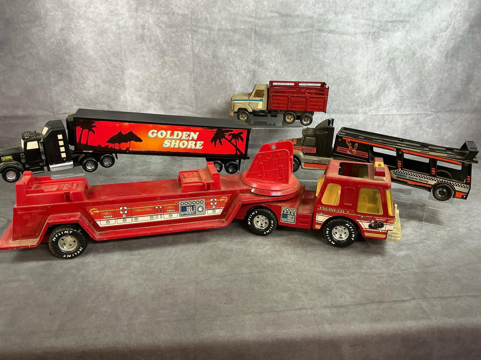 Fire Truck & Tractor Trailers: Four commercial truck toy replicas. Two tractor trailers, a farming livestock truck and a fire truck. All in fair to good condition. Fire truck measures 30.5 inches long x 5 x 5.5 inches tall.
