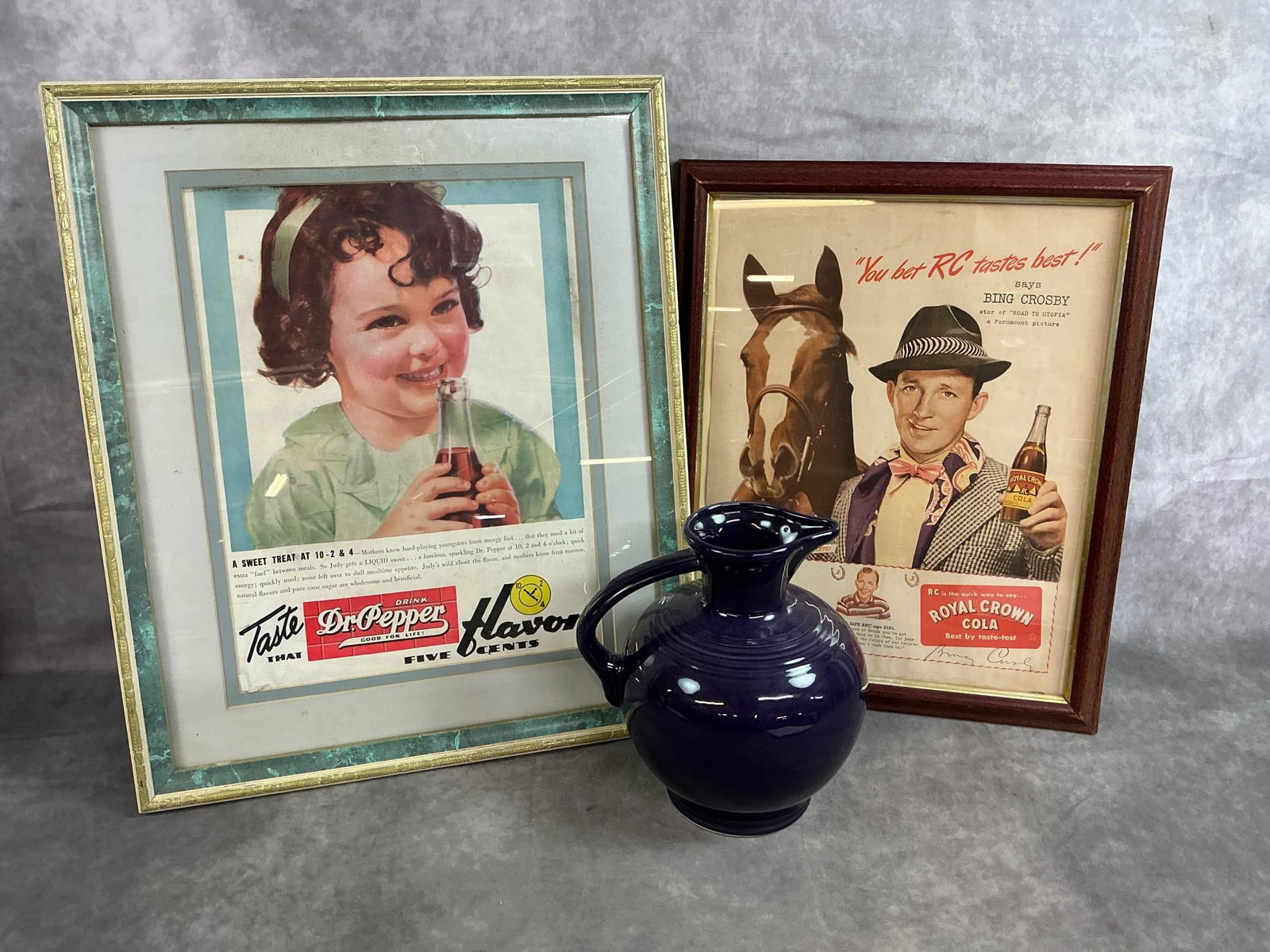Fiesta Carafe & Vintage Ads: Two framed vintage ads and Fiesta carafe. Homer Laughlin retired Plum color ceramic pitcher marked Fiesta. Dr Pepper mid 1900's framed ad and Royal Crown Cola ad with Bing Crosby in wooden frame.