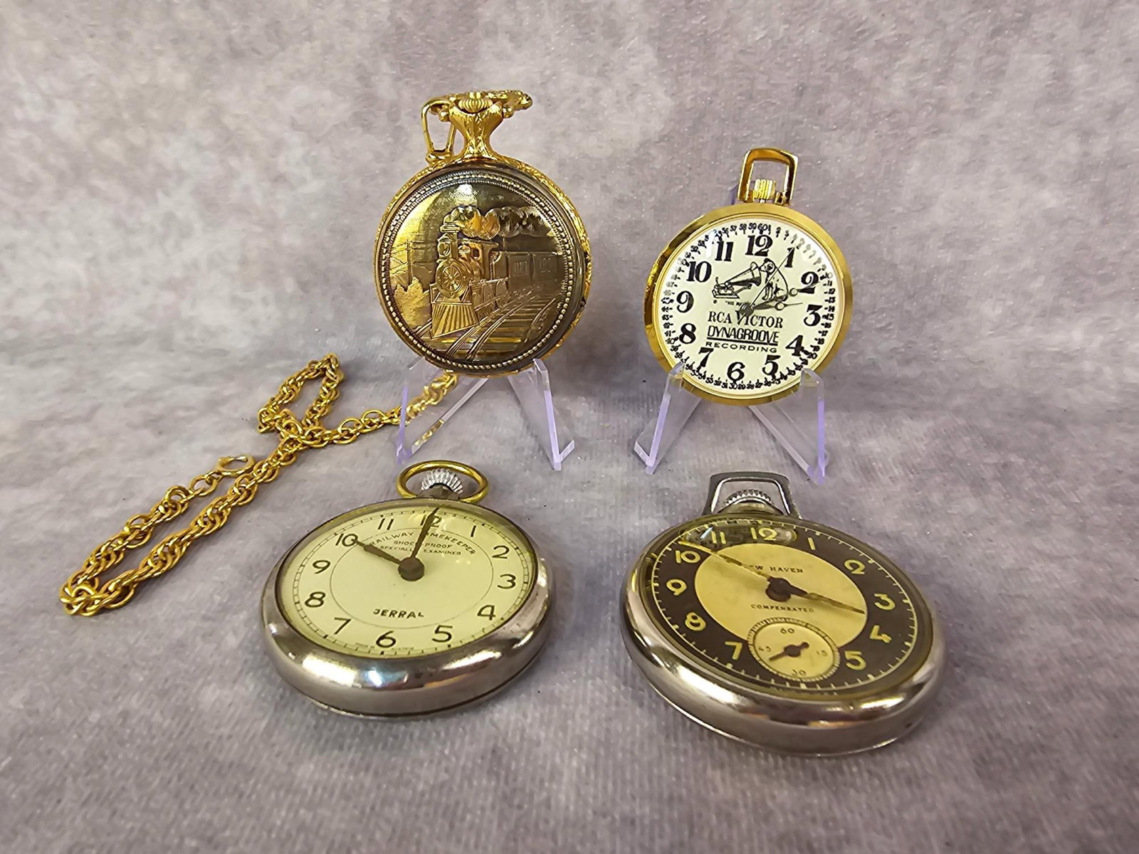 Pocket Watch Collection: Four modern men's pocket watches. Includes New Haven, Jerral Railway Timekeeper, RCA Victor advertising, and Timex. All are working except tge RCA Victor. Largest measures 1.75 inches wide.