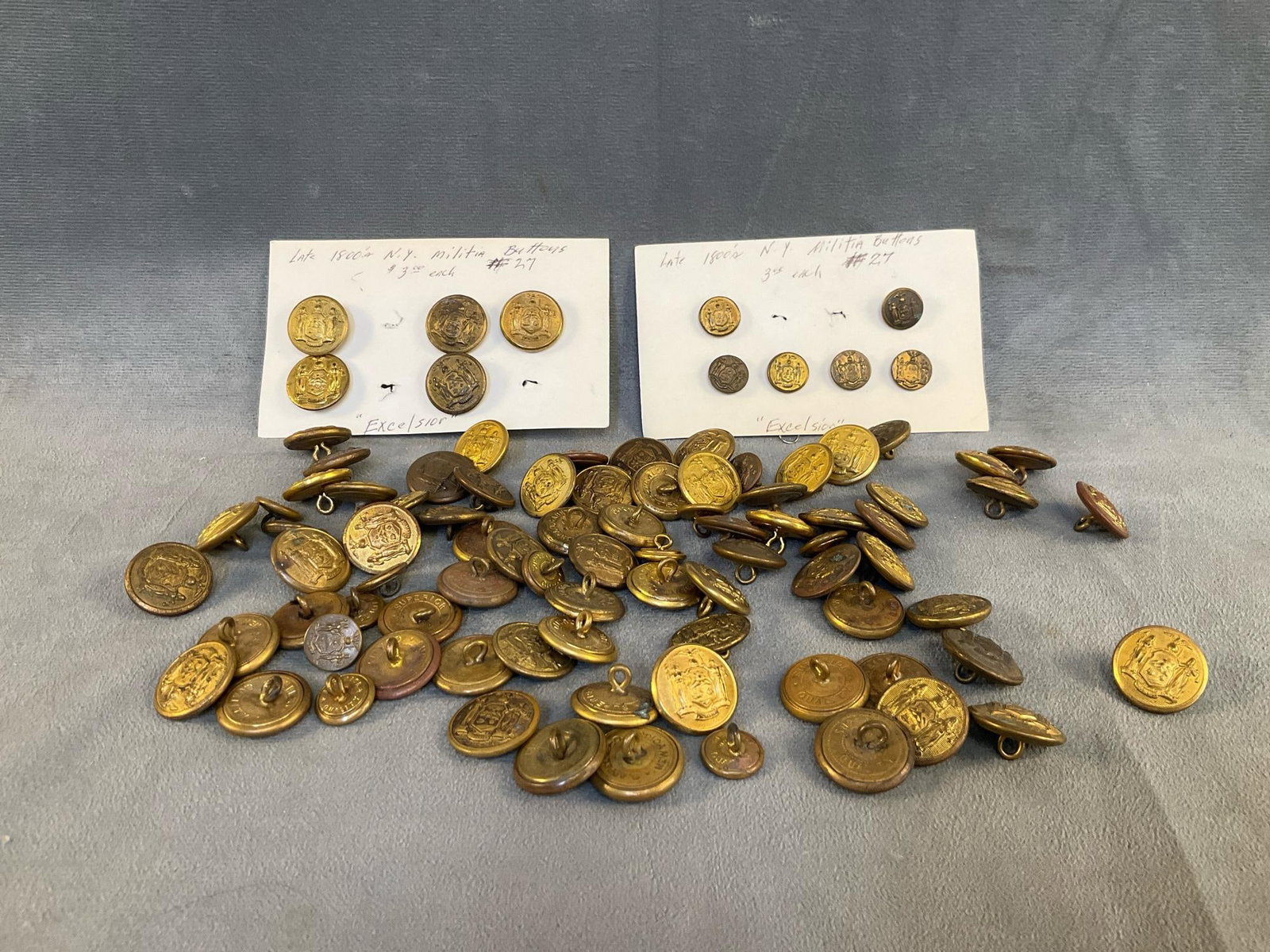 Militia Buttons: Approximately ninety five mostly "Exselsior" motto late 19th century New York State brass militia uniform buttons including Russell and J.R. Gaunt & Son Inc. buttons. Measures 1.75 inches in diameter