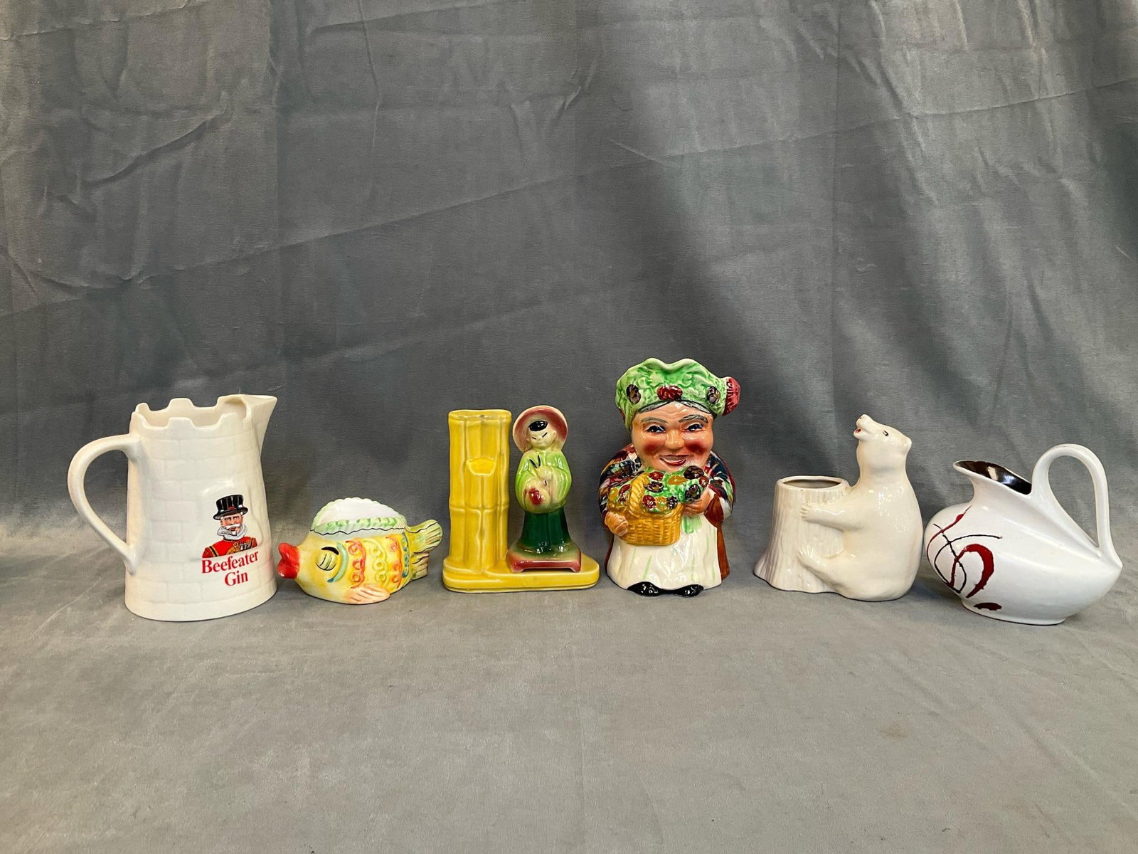 Vintage Pottery: Six pieces of mid-20 century collectible pottery. Staffordshire Toby jug made in England, Beefeater Gin jug made in England, fish bowl (small chip to rim), Chinese motif plant vase marked "U.S.A. 702"