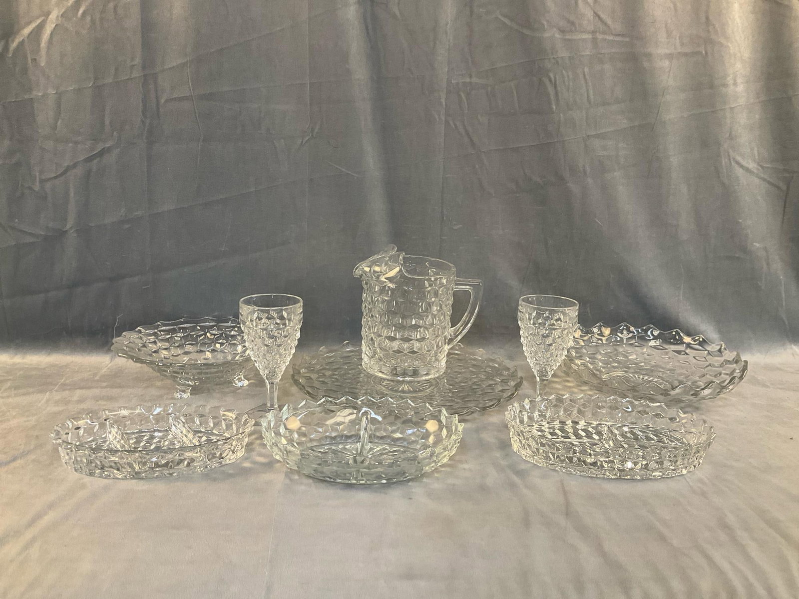 Fostoria Crystal: Nine pieces of mid-20th century Fostoria Glassware. Pitcher and two goblets, three relish trays, one platter and two bowls. Good condition. Platter measures 15 inches in diameter x 1.25 inches tall.