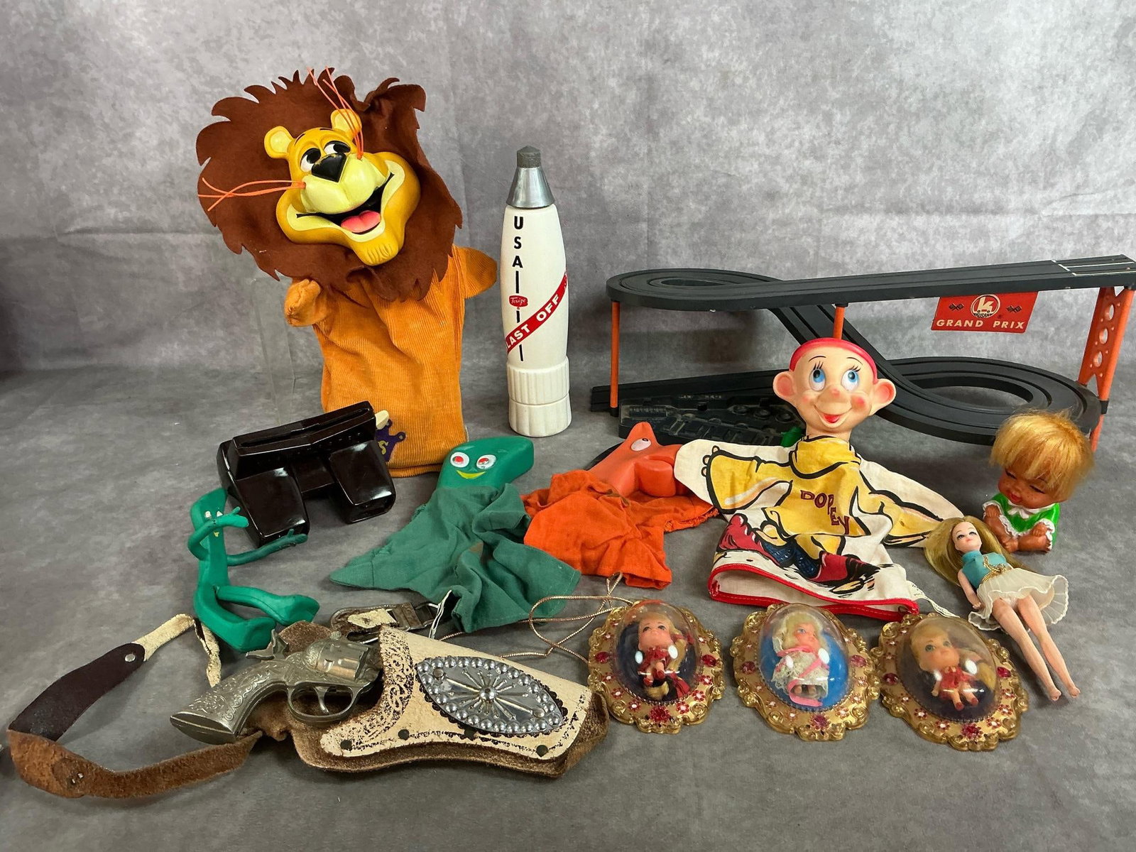 Puppets, Race Track, Dolls, & More: Fourteen mid 1900's toys. Includes Linus the Lionhearted puppet, Walt Disney Dopey puppet, Kusan Grand Prix Race track with one car, and Hubley play pistol with holster. Also, three LuckyLocket