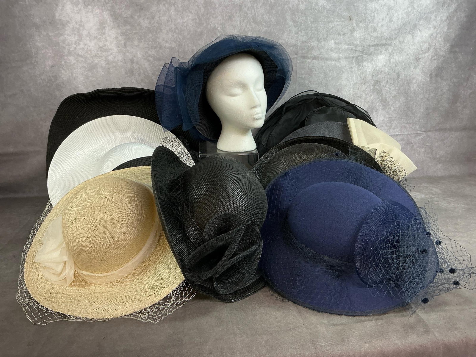 Ladies' Summer Hats: Ten late 1900's to modern age ladies' floppy hats. Includes straw, fabric, and satin, with netting, bows, and flowers. Largest black hat is worn, otherwise hats in good condition. Largest measures 18 