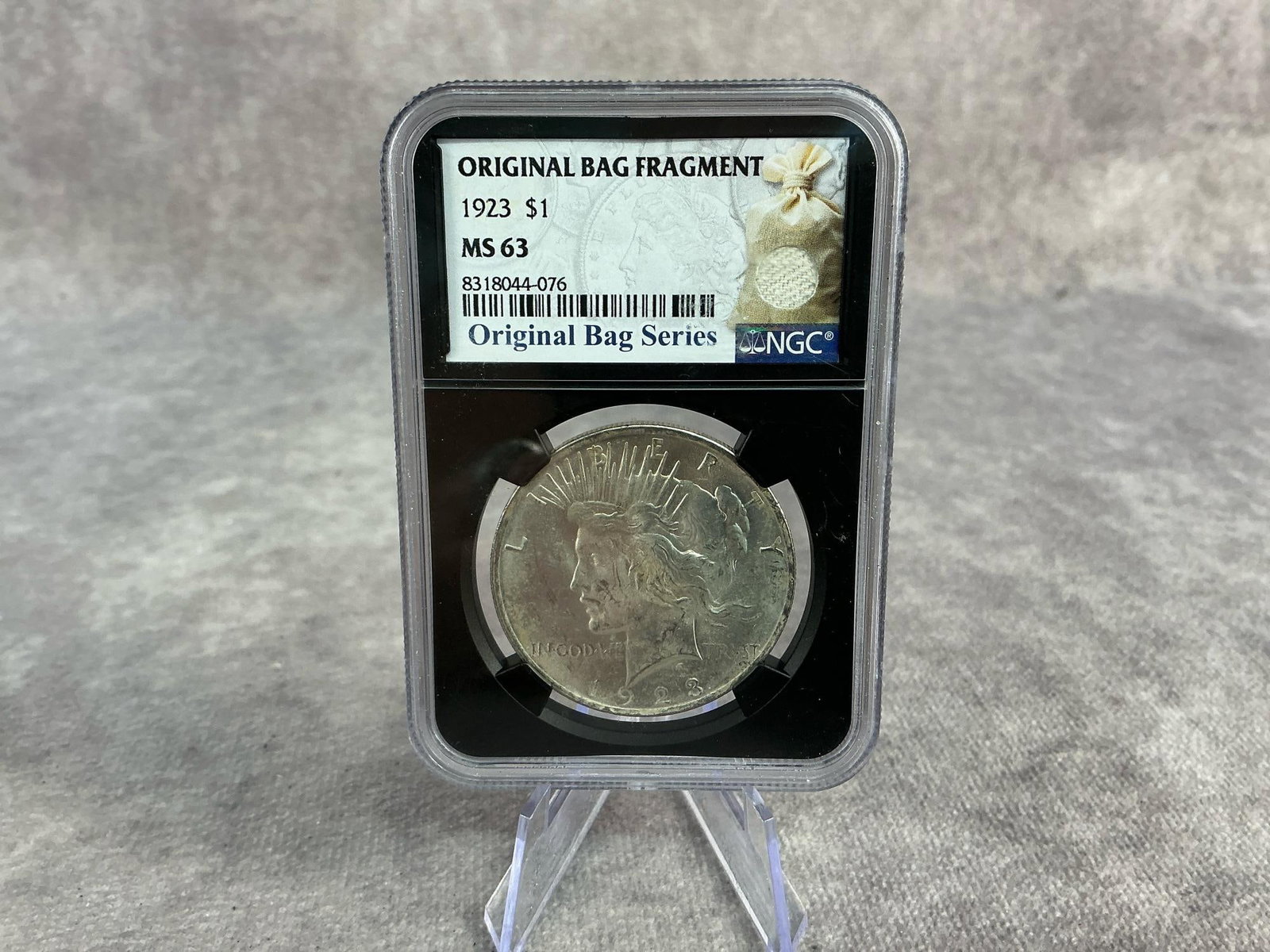 Peace Dollar: 1923 US Peace Silver Dollar, MS 63, graded by NGC. Certification number 8318044-076. Measures 2.25 inches wide x 3.25 inches tall.