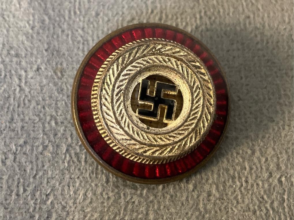 Nazi Badge: Circa 1939 German NSDAP (Nazi Party) political visor cap cockade. The cockade features a black enameled swastika inside a gilt wreath and a translucent red enameled base. Reverse is marked "RZM M