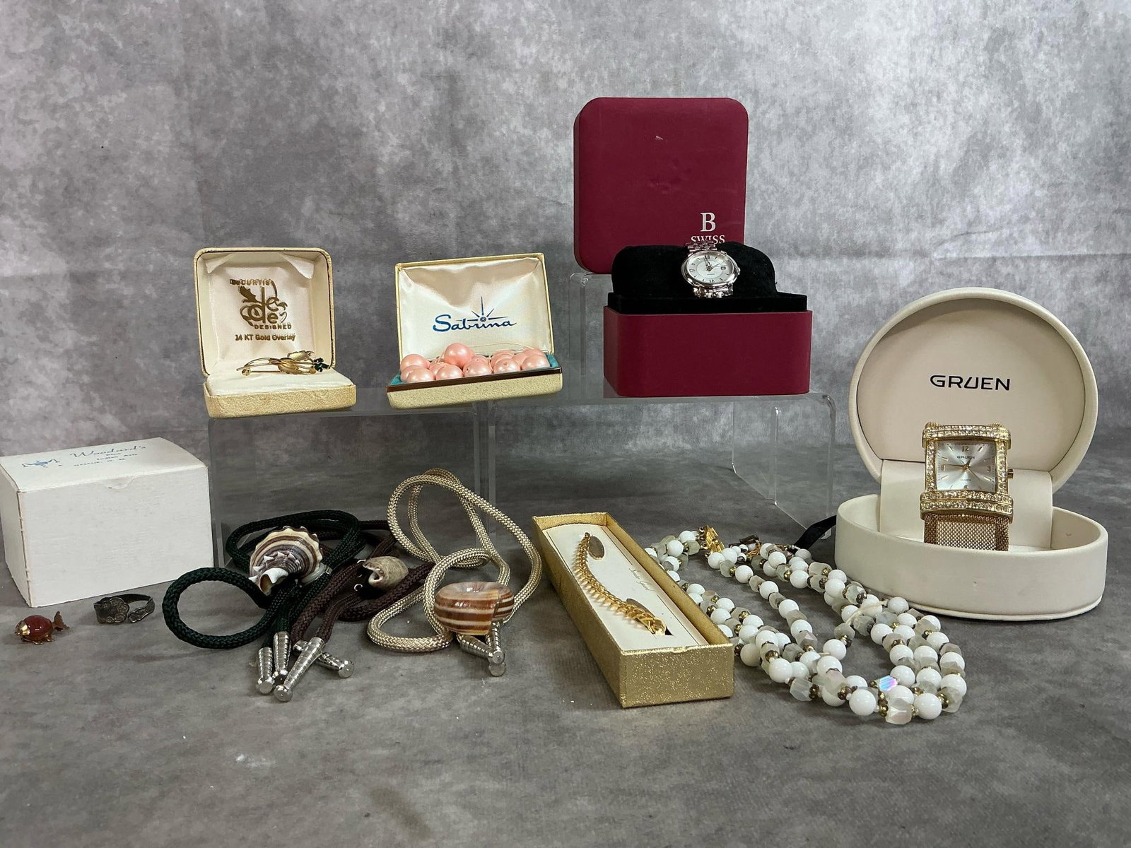 Watches, Pins, Bolo Ties, & More: Ten mid to late 1900's jewelry. B Swiss women's analog working wristwatch in box, Gruen bezel women's watch (untested), sweater guard in box, and white and frosted beads necklace. Includes three