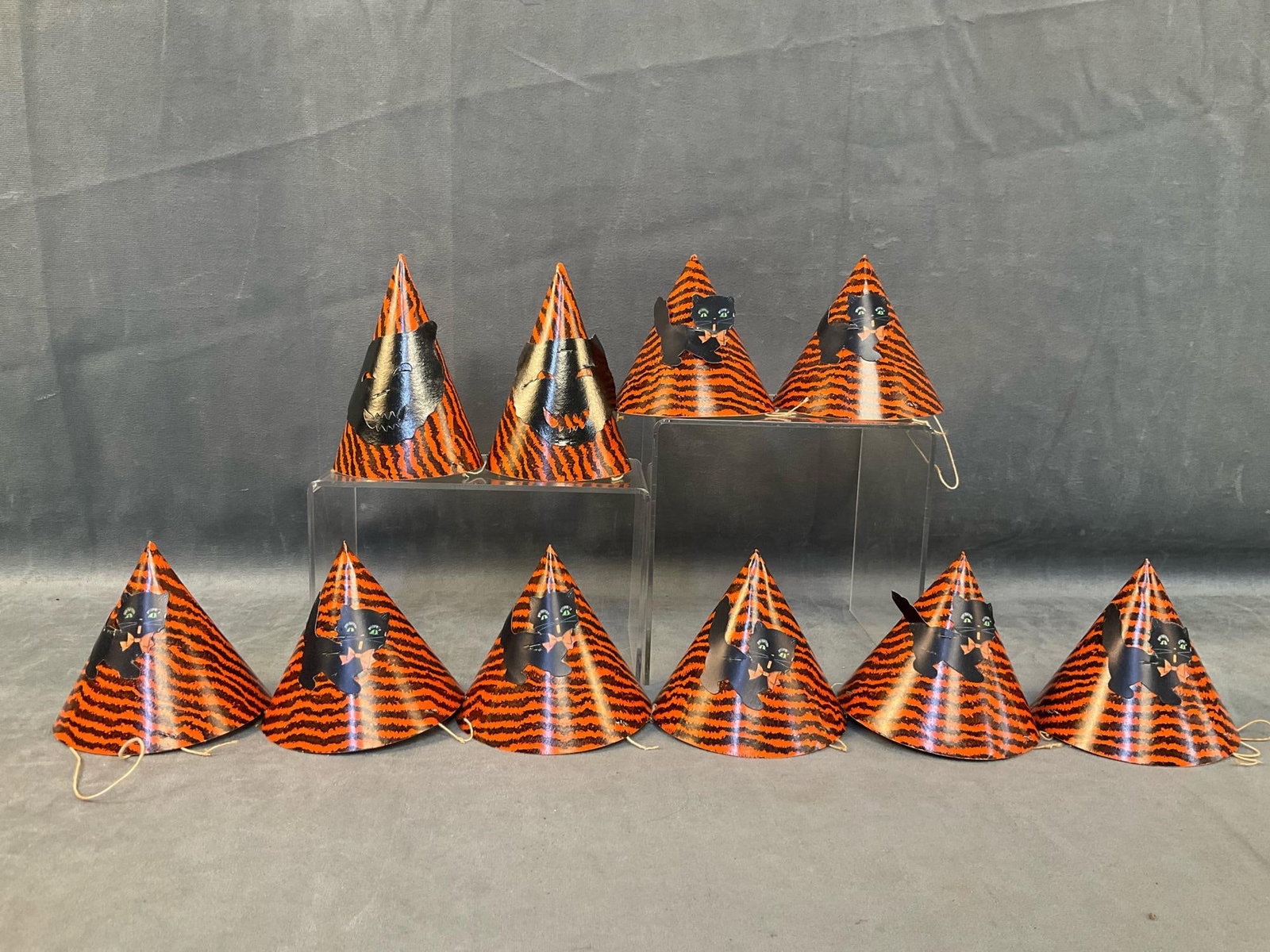 Halloween Hats: Ten 1950's-1960's children's black and orange striped Halloween party hats with die cut out cats and string neck straps. Two black cat faces and eight black cats. Two cats with bent cut outs,