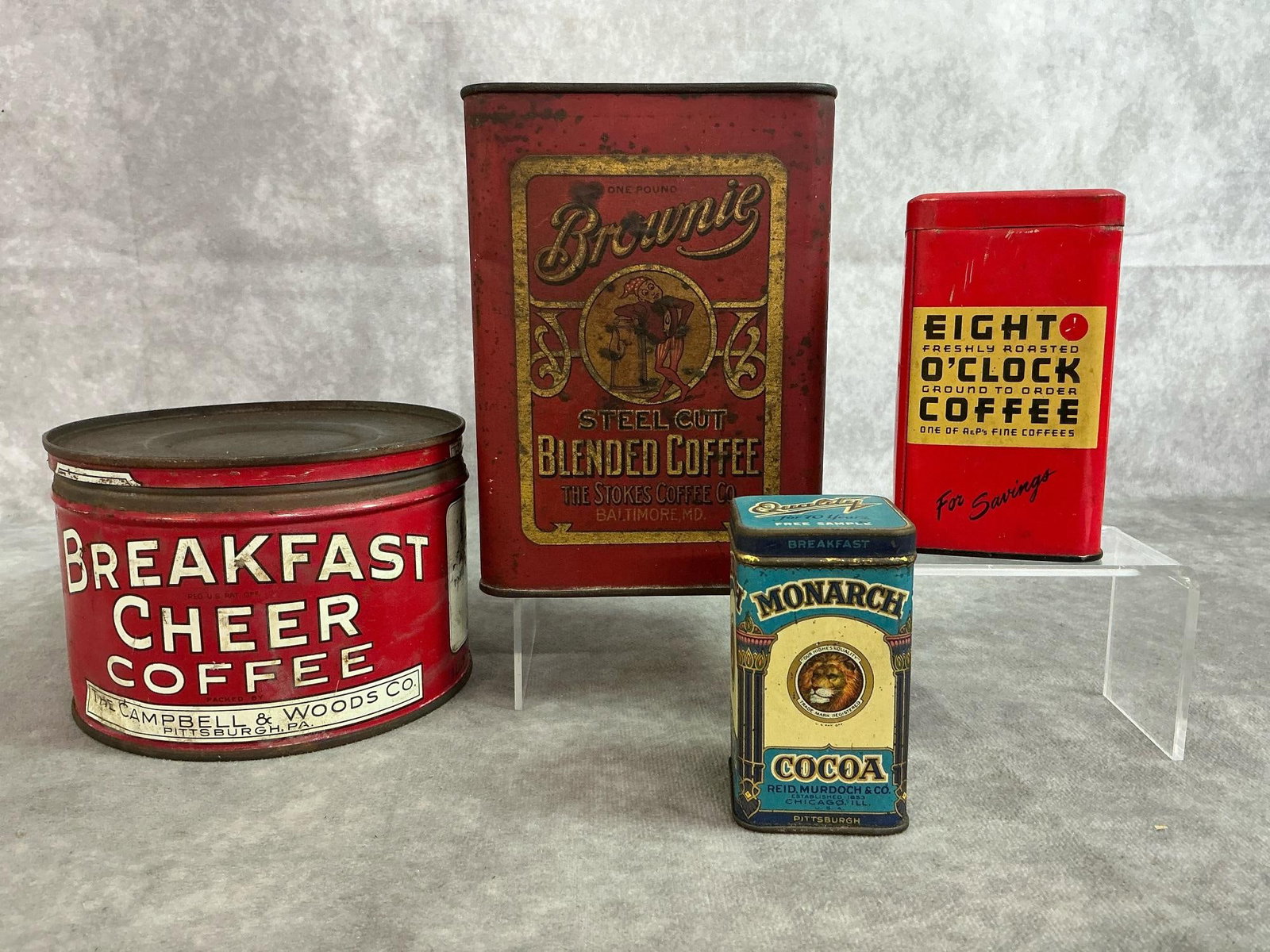 Coffee & Cocoa Tins: Four early 1900's tins. Brownie Blended Coffee tin, Breakfast Cheer Coffee Tin, Eight O'Clock Coffee coin bank tin, and Monarch Cocoa sample tin. Rust present. Brownie Coffee measures 4 inches wide x