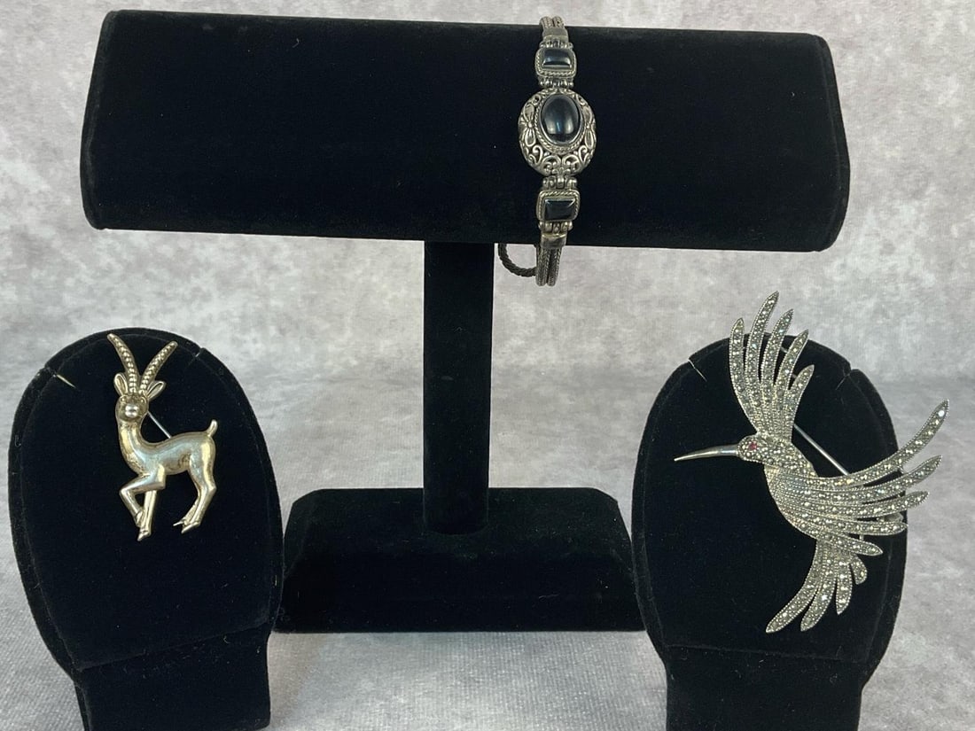 Sterling Silver Bracelet & Brooches: Three sterling silver jewelry pieces. Lot includes one toggle clasp sterling silver and onyx bracelet, one vintage Coro Gazelle Antelope Brooch and one Judith Jack marcasite and ruby brooch. All in