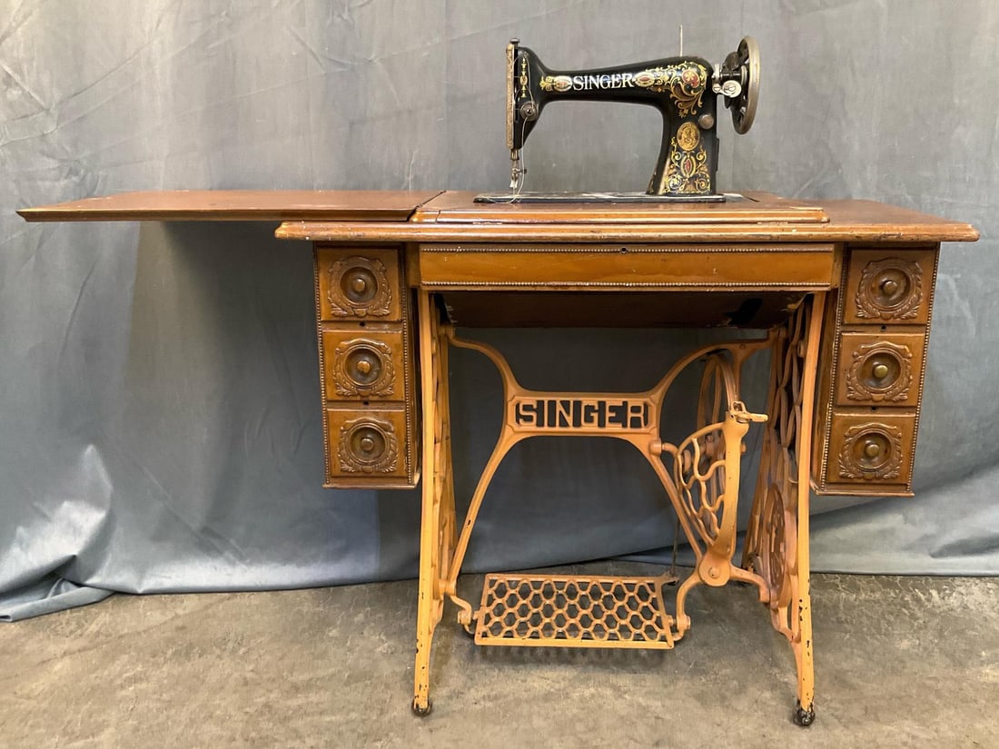 Sewing Machine: Early 20th century Singer treadle sewing machine with three side drawers and one central door. Painted with paint splatter and original belt broken. Not tested, otherwise good condition. Measures 37
