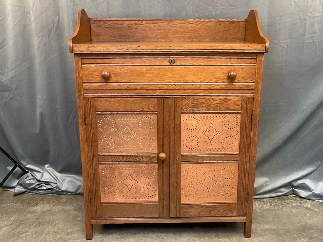 Pie Safe: Early 20th century pie safe with four copper tins, gallery, paneled sides, pegged mortise and tenon construction and one upper drawer above two lower doors with one interior shelf. Oak, poplar and