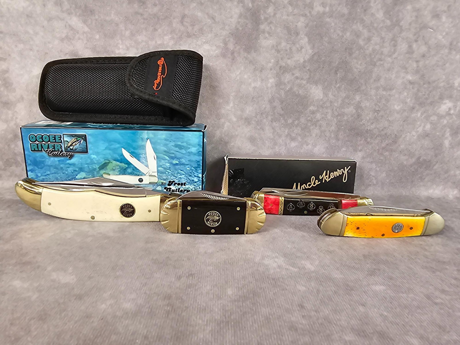 Collectible Knives: Four modern knives, two Ocoee River knives, Uncle Henry, and a Rough Rider. One Ocoee River knife and the Uncle Henry have the original box. Uncle Henry is missing a metal band from the handle.