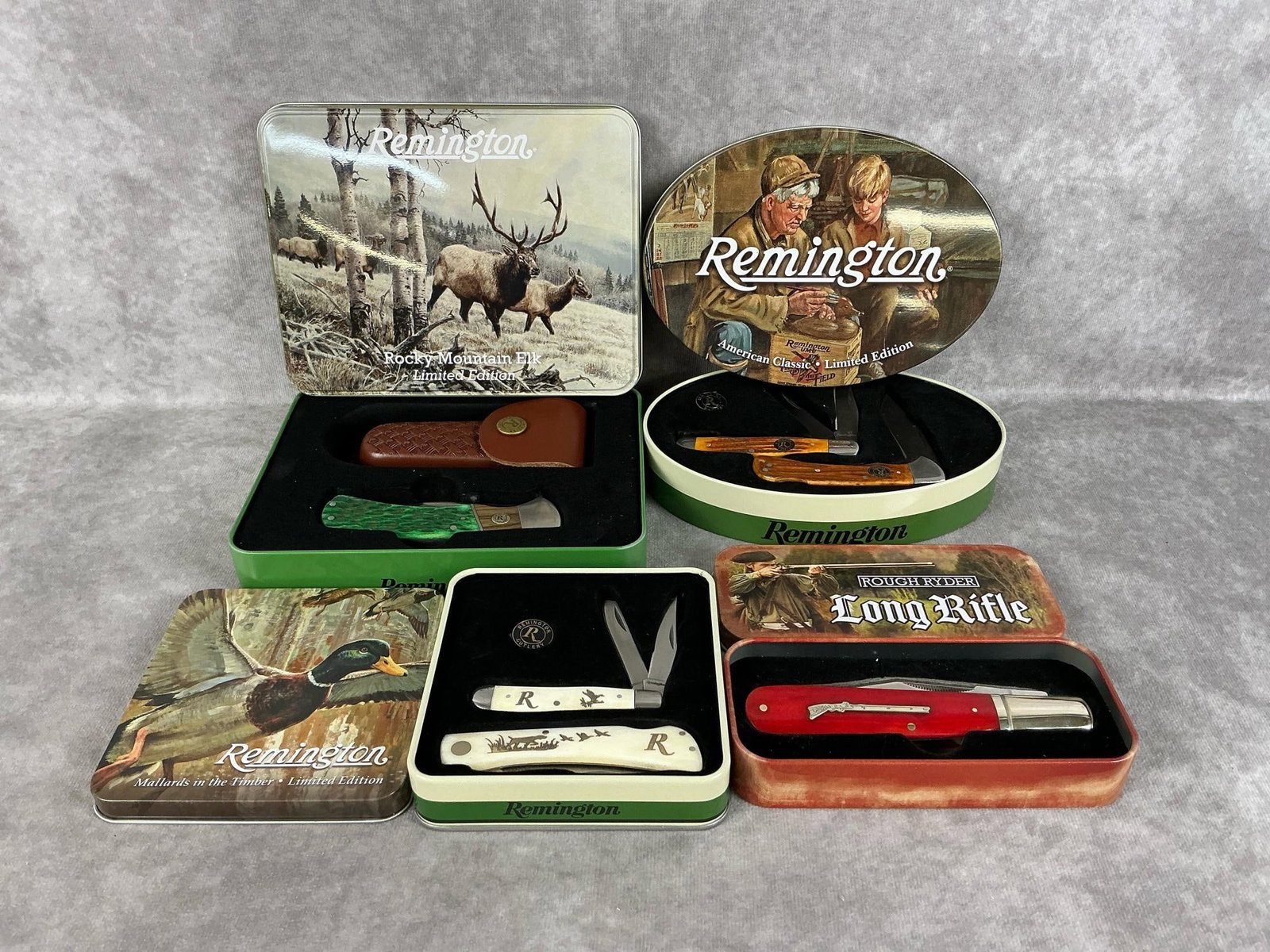 Remington & Rough Ryder Knives: Four modern collectible knives, three Remington tins and one Rough Ryder. All knives are new and in good condition. Largest tin measures 7.25 inches wide x 5.5 inches tall.