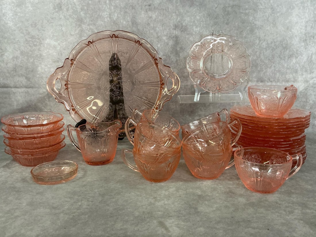 Jeannette Glass: Thirty-four mid century Jeannette Glass cherry blossom pink glass. Includes serving tray with handles, 17 saucers, 10 cups, 5 dishes, creamer and coaster. In good condition. Tray measures 10.5 inches