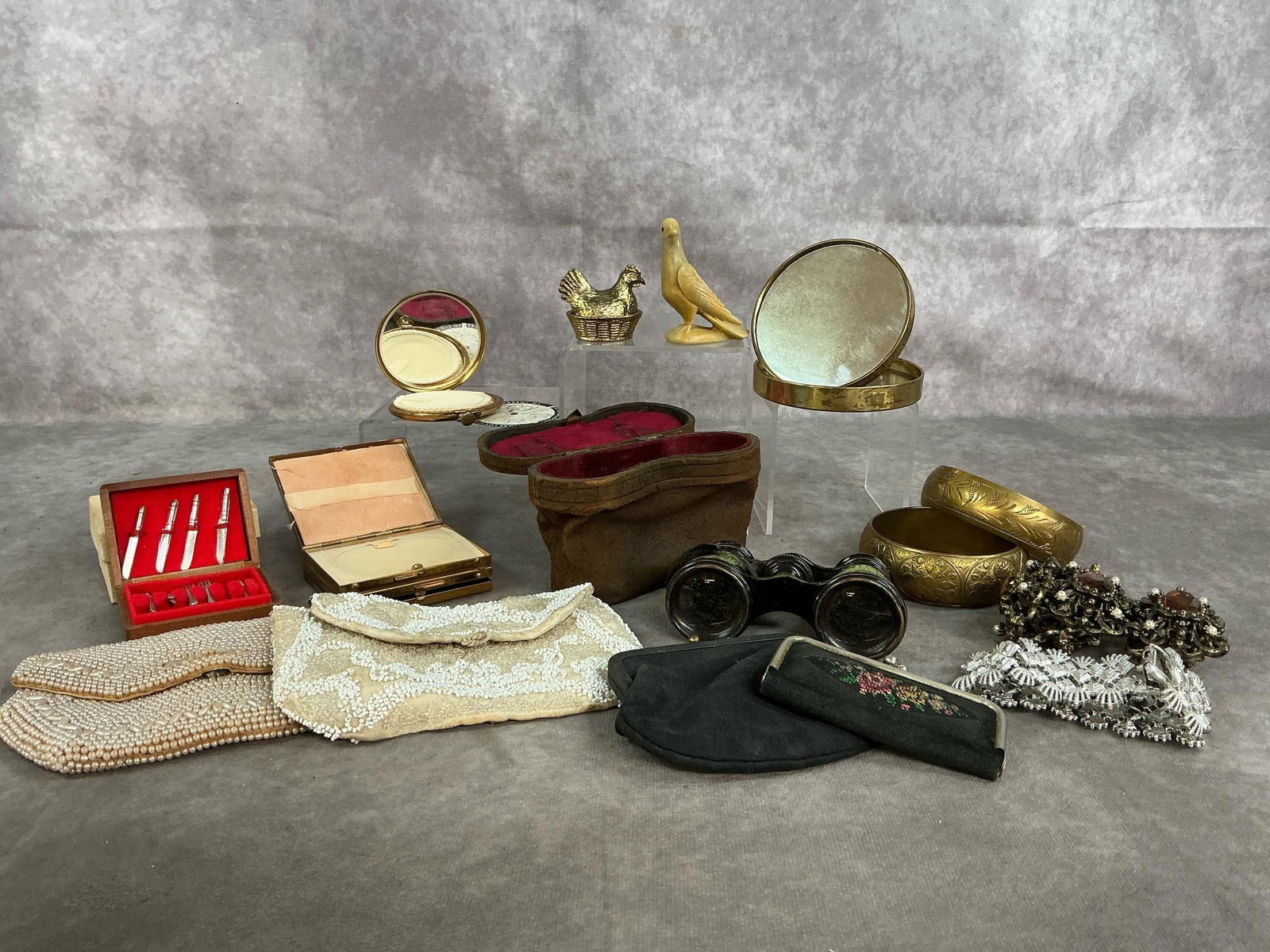 Purses, Bracelets, Hand Mirrors & More: Sixteen early to late 1900's ladies' finds. Four vintage purses, four bracelets, three compacts with mirrors, opera glasses, and toy cutlery chest. Includes miniature brass hen on nest and hand