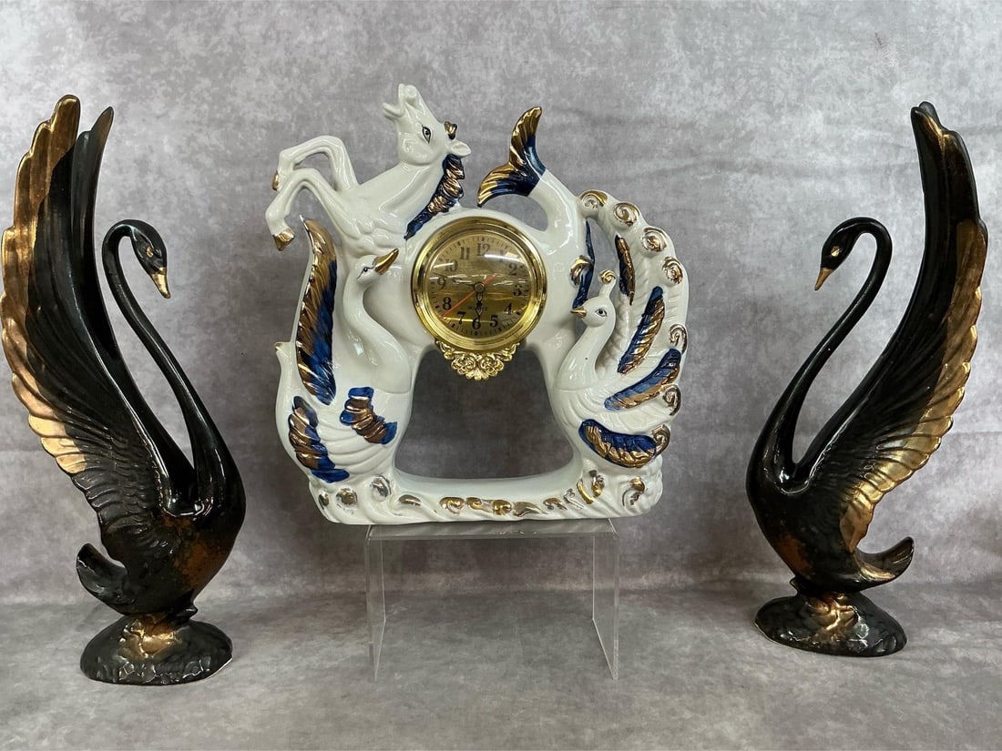 Ornate Clock & Swans: Three mid 1900's pieces. Two black and gold glazed ceramic swan figures. Porcelain handpainted table clock with peacock, duck, horse and fish on ornate base. Clock needs repaired battery box,