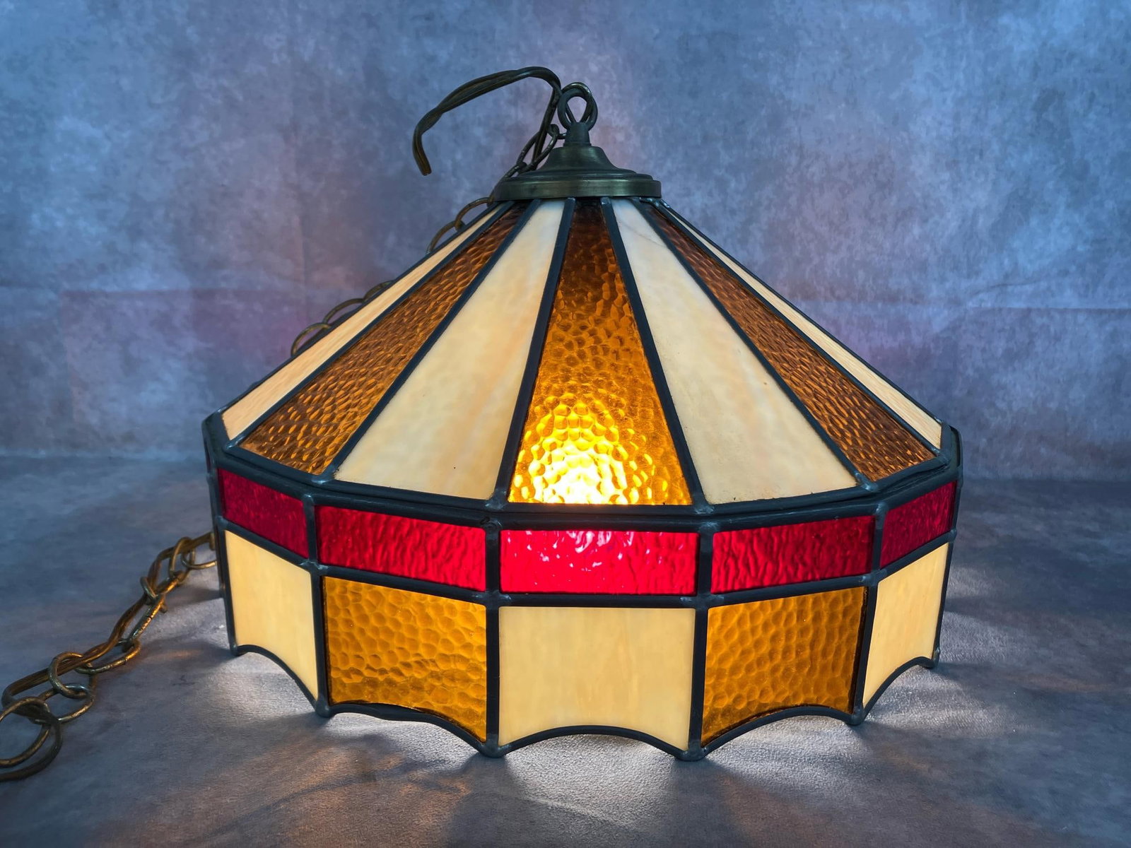 Hanging Stained Glass Lamp: Late 1900's Tiffany style stained and slag glass swag pendant lamp. Hanging lamp with long chain in red/brown, amber, and cream glass inserts. Slight tarnish, bulb socket is loose. Working light. Meas