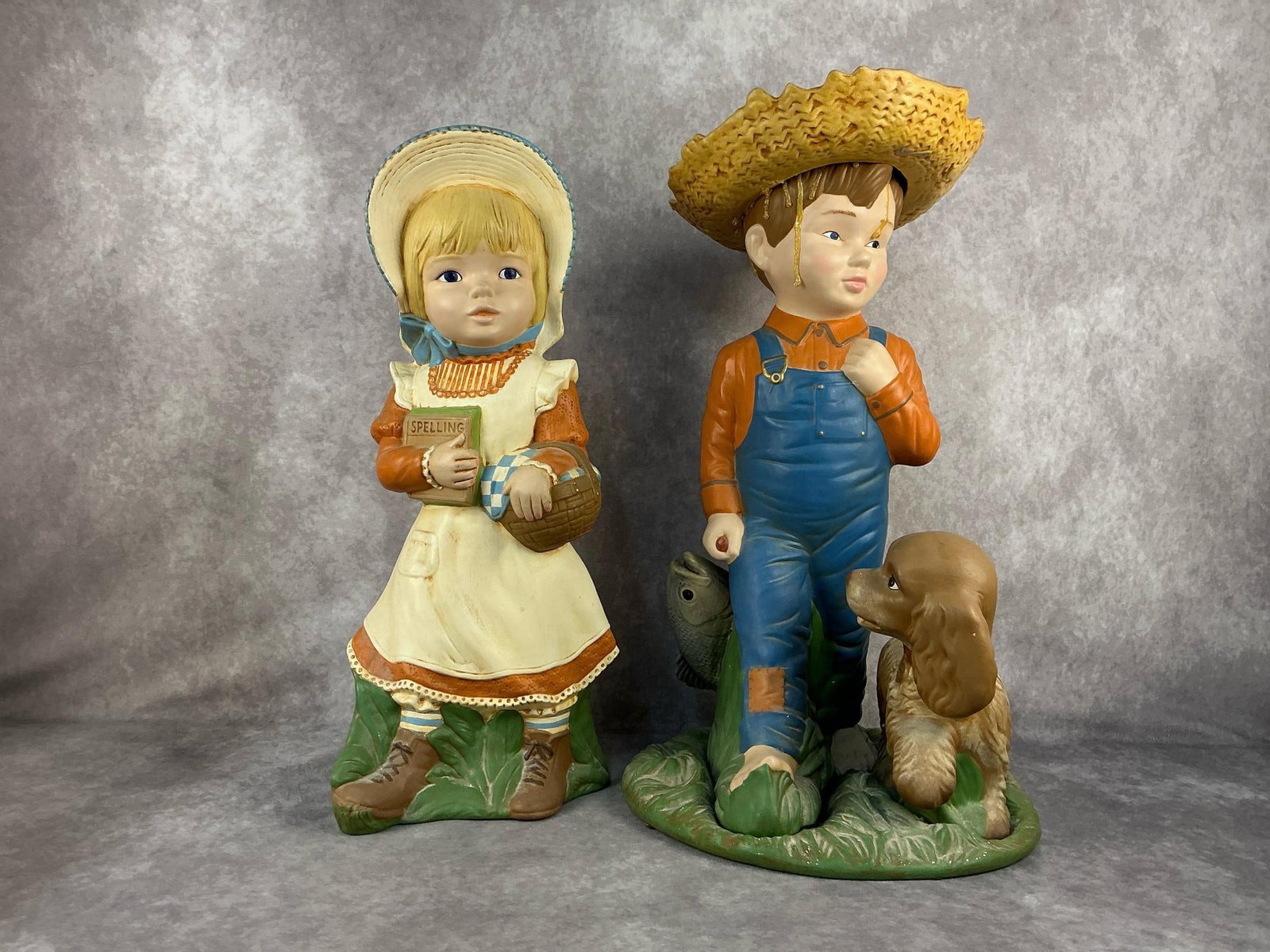 Boy & Girls Statues: Vintage ceramic garden statues. Both have chips in the ceramic throughout and the boy is no attached to base, otherwise good condition. Boy measures 12 inches long x 7 x 20 inches tall.