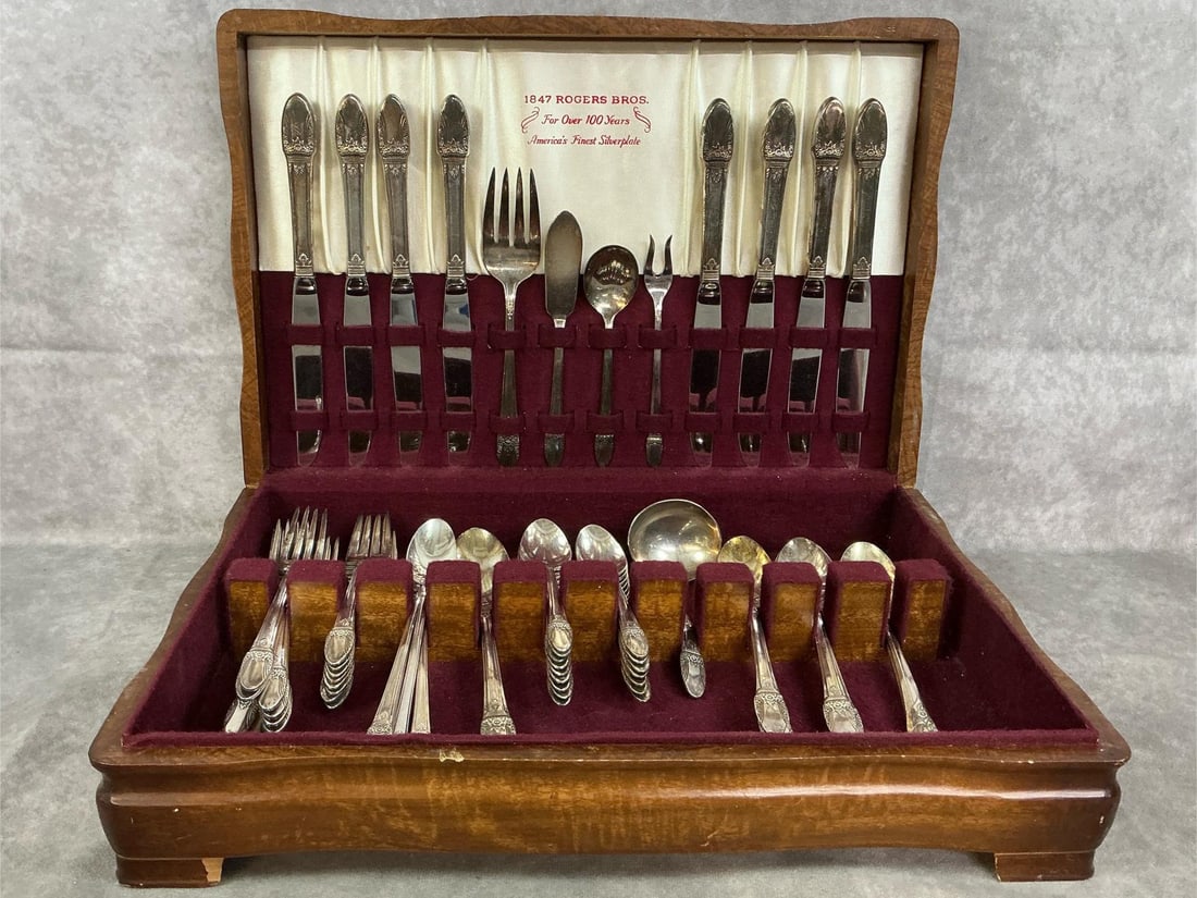 Rogers Brothers Silverplated Flatware: Seventy pieces 1930's siverplated flatware in wooden display case. First Love pattern by 1847 Rogers Brothers. Slight tarnish present, otherwise in good condition. Includes several serving pieces.