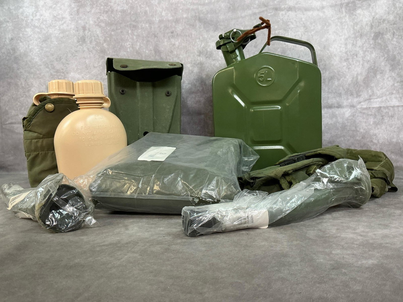 Jerry Can, Chemical Suit, Canteens & More: Nine new or gently used army surplus items. Metal 5L Jerry can, two spouts, and two plastic canteens, one with cover. 1986 Czech Chemical suit, two small ammunition cases, and tri-fold entrenching