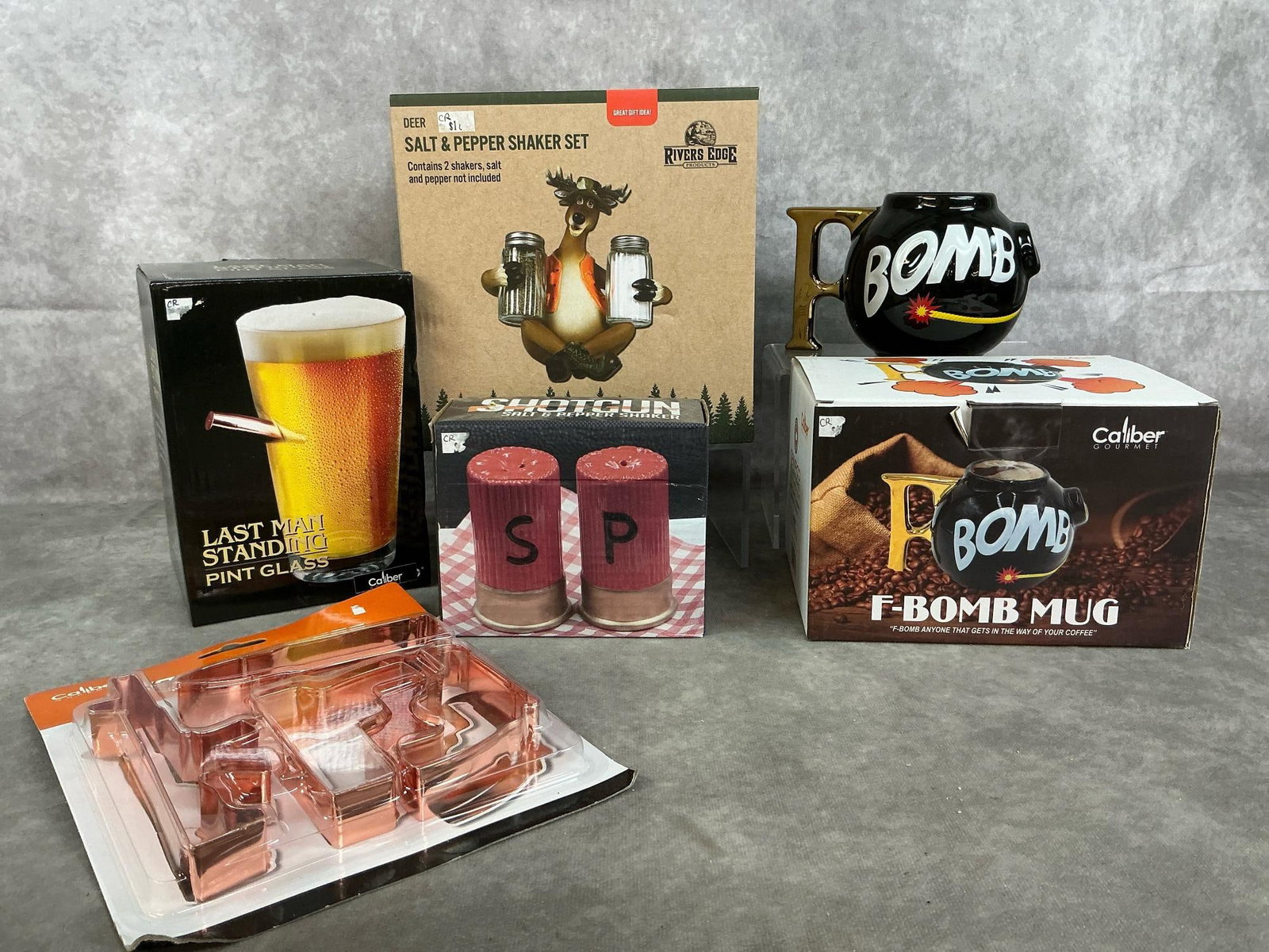 Novelty Salt & Pepper Shakers, Mug, Glass, & Cookie Cutters: Five packaged novelty items. Deer salt & pepper set, shotgun salt & pepper set, "F-bomb" mug, "Last Man Standing " pint glass, and tactical cookie cutters. In original taped boxes. Deer salt & pepper