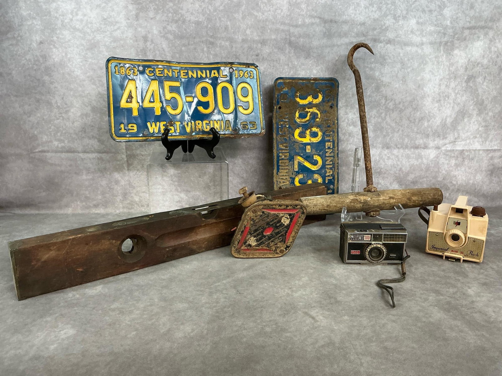 Antique Level, License Plates, Hay Hook, & More: Seven early to mid 1900's tools, cameras, and license plates. Wooden level, hay hook (or cargo hook), 1963 West Virginia license plates, cameras (untested), and more. Items have rust and considerable
