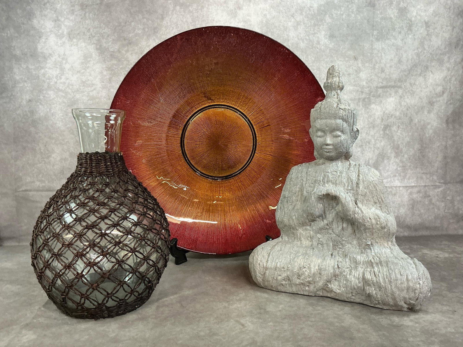 Decorative Home Accents: Three modern age decorative items. Large glass bowl with red fade to amber center and gold tone back. Molded A&B 11" accent Buddha statue, and large glass decanter with woven netting. In good