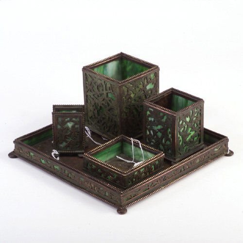 APOLLO STUDIOS five-piece smoking set in: APOLLO STUDIOS five-piece smoking set in the style of Tiffany, with pierced panels of flowers covered in verdigris patina and lined with green slag glass: cigarette box, match box, match holder, ashtr