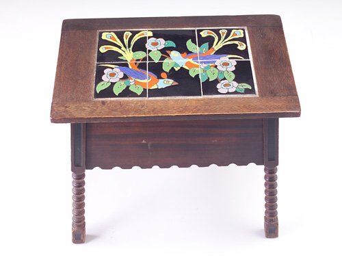 TAYLOR Fine and rare tile-top sewing table with a: TAYLOR Fine and rare tile-top sewing table with a six-tile panel depicting birds of paradise in bright polychrome on black ground, mounted in a flip-top Mission table with turned legs. A few short scr