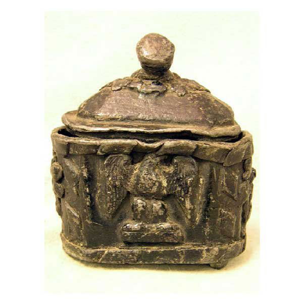 Boxes - A nineteenth century lead tobacco jar, th: Boxes - A nineteenth century lead tobacco jar, the rectangular rounded vessel cast with panels of eagles and vases of flowers, raised on ball feet, the lid with bust figural handle. (6in)