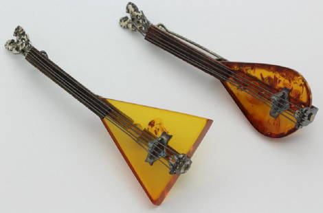 2 Sterling Silver Baltic Amber String Instrument Brooch: Lot of two instrument brooches. Crafted of sterling silver amber and wood. marked 925. Features a Mandolin and Balalaika motif. Pin backs are secure. Measure 2.5" long. Total weight is 13.8 grams.