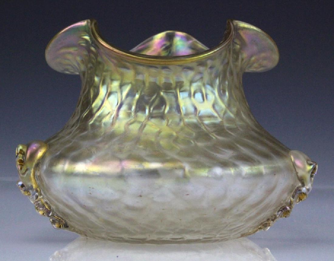 Scalloped Nautilus Type Iridescent Art Glass Vase: Nautilus style art glass vase. Features a squat oval form with a textured iridescent detail. Three sections of the vase have an applied spiral glass decoration. The rim has a scalloped edge. Measures 