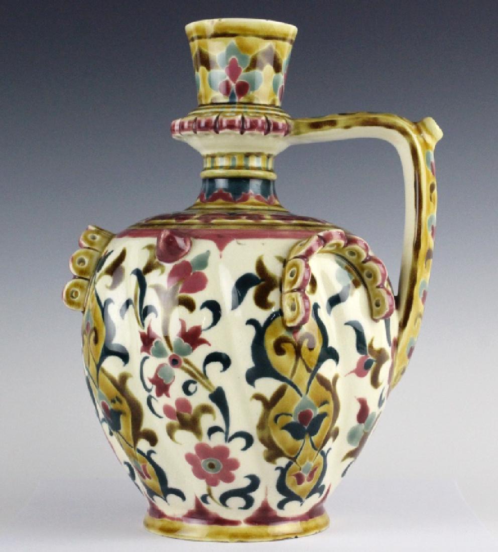 Zsolnay Polychrome Applied Decoration Jug 11 3/4": Zsolnay Hungarian polychrome jug. Features a floral motif on the body and colorful floral patterns near the top. The body and handle have applied decoration. Blue Zsolnay mark on base. Measures 11 3/4