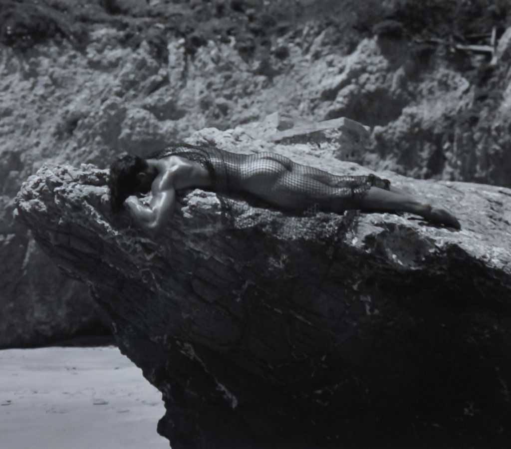 Len Prince 1953- American Erotic Photograph: Signed limited edition gelatin silver print by Len Prince (1953-Michigan) \"El Matador Beach Bob w/Net 1994\" depicts a homoerotic image of a male nude on a rocky shoreline. Artist signed, titled, dat