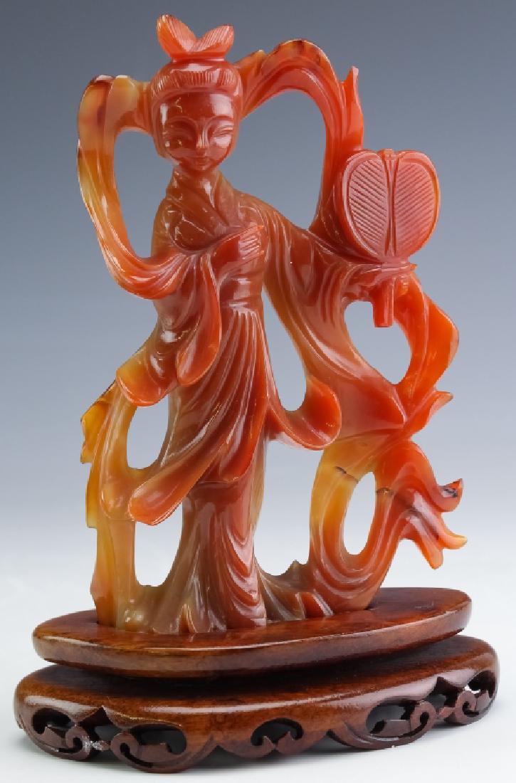 Chinese H-Carved Carnelian Agate Quan Yin Statue: Carved Chinese carved Quan Yin figurine. Features the form of Guan Yin (Guanyin, Kwan Yin) with reticulated ribbon behind her as well as a fan in one hand. Fixed to wood base. Measures 7" x 5" x 2 3/4