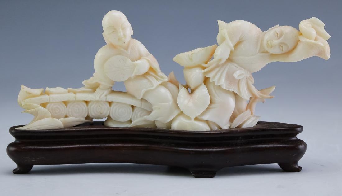 Chinese Carved Angel Skin Figural Coral Art Statue: Hand carved precious solid angel skin coral. White with spots of pink and features two young boys on bench with lotus blossoms. Comes with custom fitted hard wood stand. Measures approximately 6 1/4" 