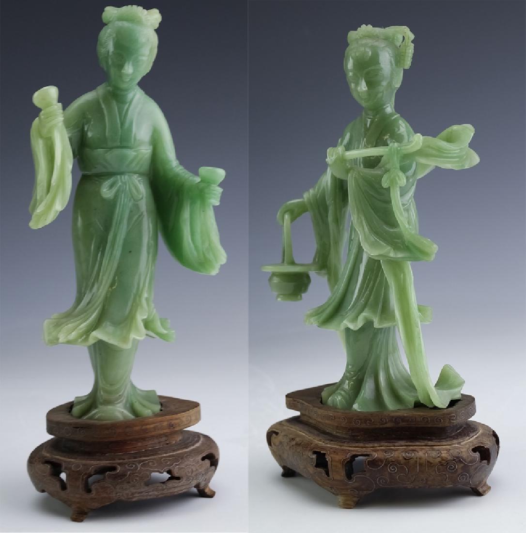 PAIR of Chinese Carved Green Jade Quan Yin Statue: Pair of carved figures in green jade. Sculptures feature one figure holding a rod in one hand and a bucket in the other. The second figure is holding a pair of vessels in her hands. Both come on wood 