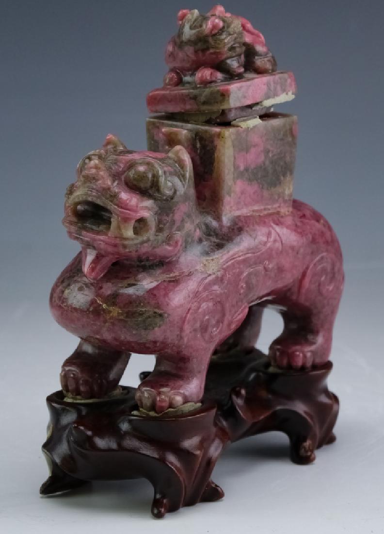 Chinese Carved Rhodonite Lidded Foo Dog Sculpture: Old Chinese export carved Rhodonite foo dog figure statue. Figurine features the form of a reticulated foo dog with figural handled lid. Comes fixed to a wood base. Measures 6" x 5". Good overall cond